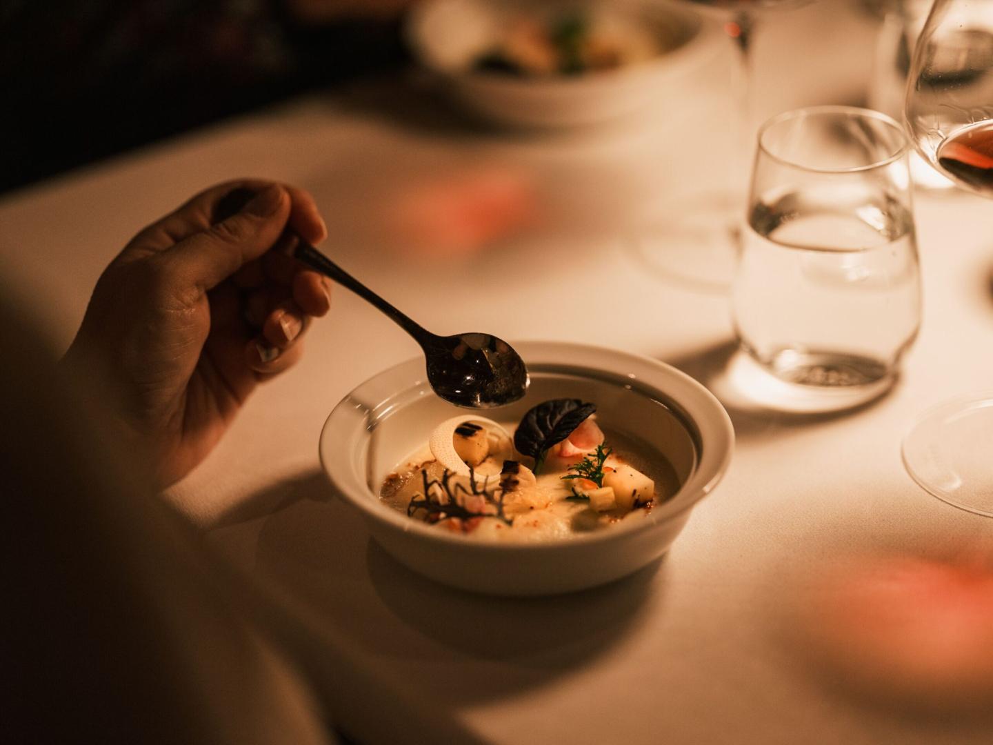 Dining with elegance, illuminated bowl of gnocchi with herbs on a softly lit table.