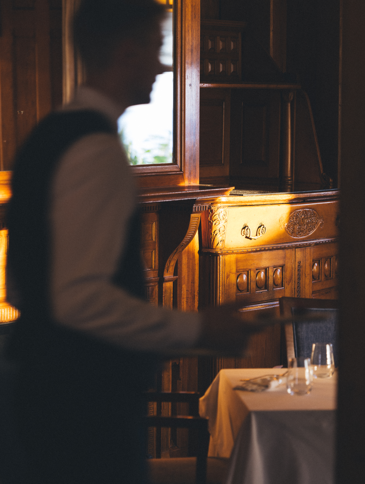 Waiter carrying tray in dimly lit restaurant.