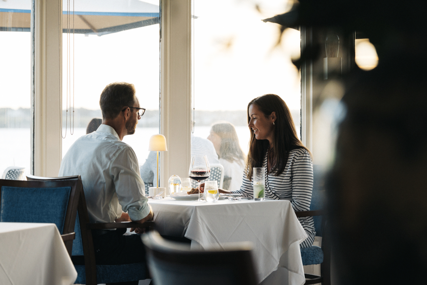 A couple dining by a window in a softly lit restaurant.