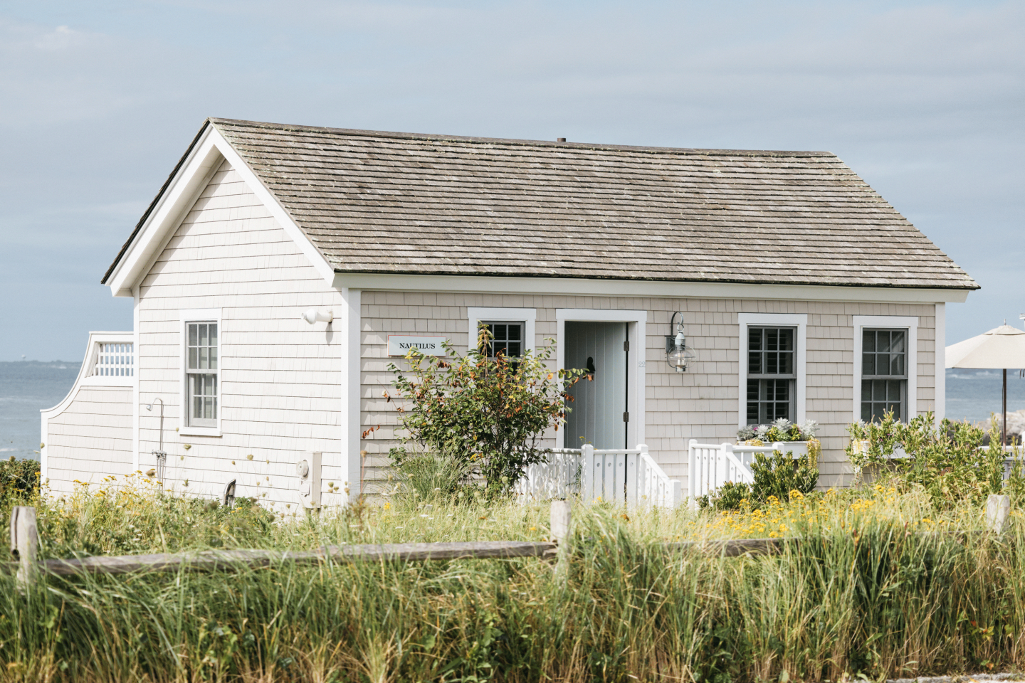 Cozy white cottage with garden, blue sky background.