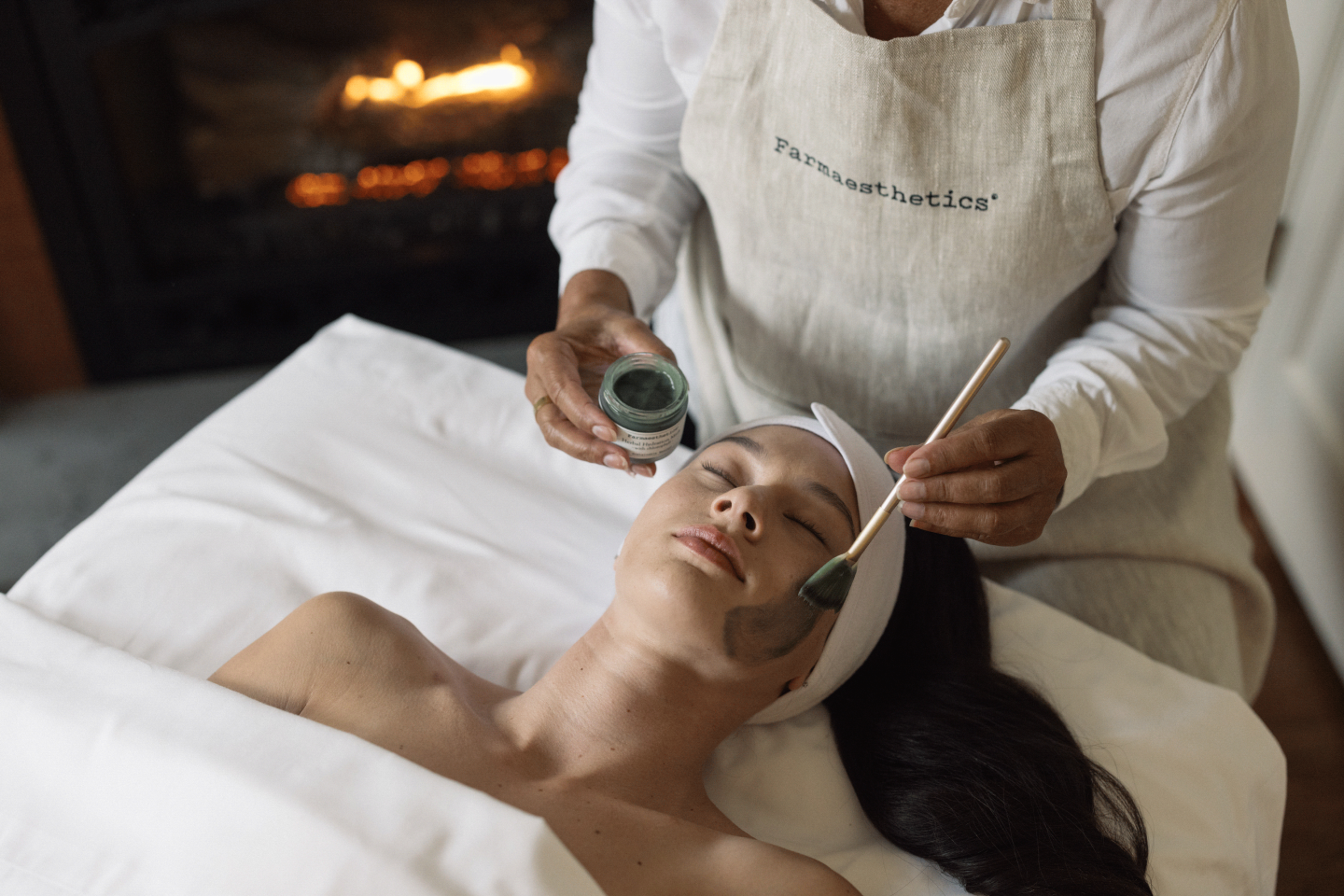 Spa treatment with mud mask applied by an esthetician on a relaxed woman.