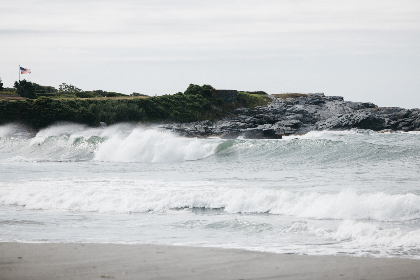 Waves crashing on a rocky coastline under a cloudy sky.