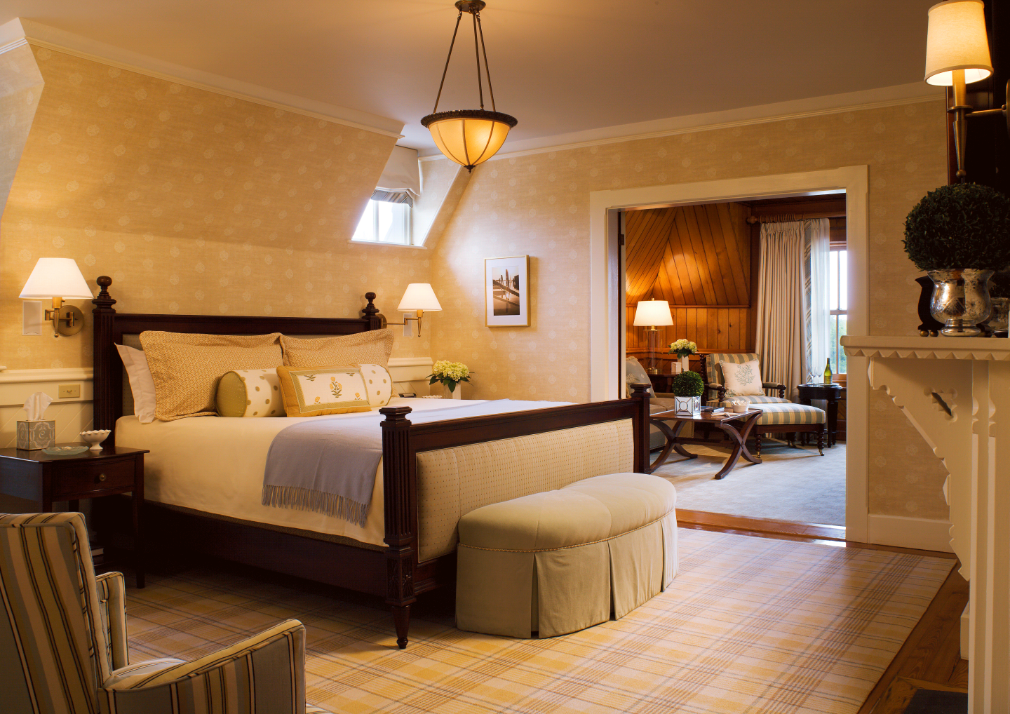 Cozy bedroom with a large bed, soft lighting, and a sitting area in warm tones.