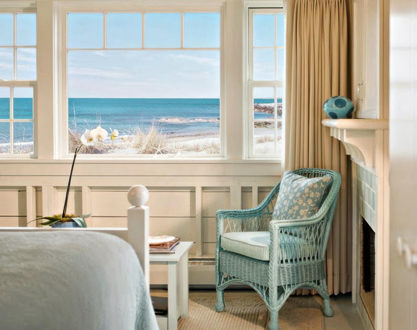Bedroom with a sea view, blue wicker chair, and an orchid on a table.