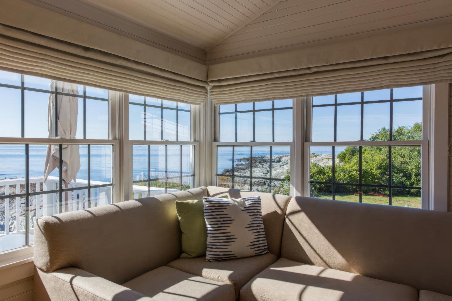 Sunny room with beige sofas, large windows, and ocean view.