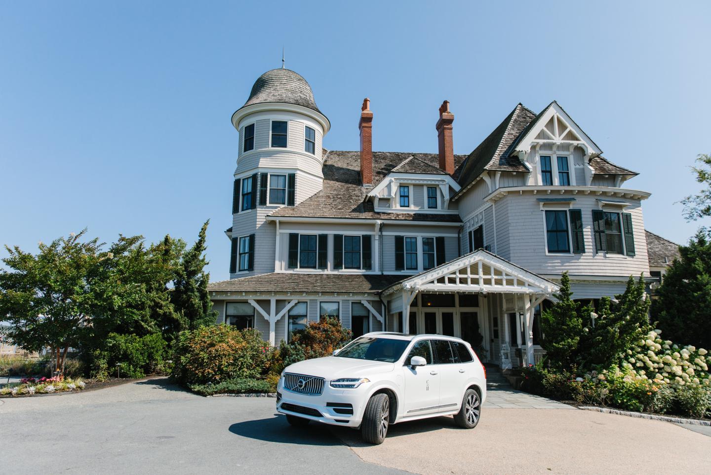 White SUV parked in front of a large Victorian-style house.