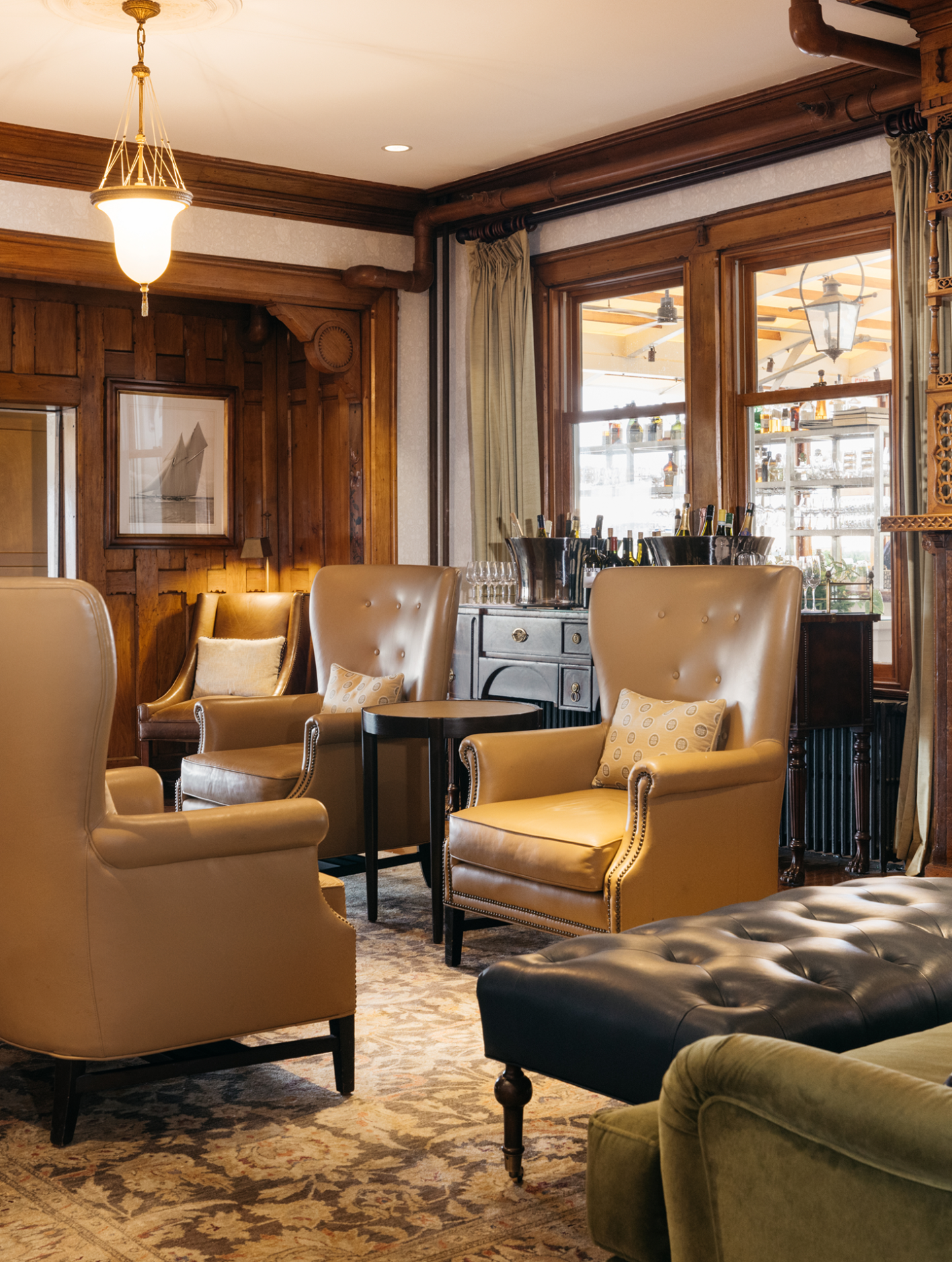 Cozy lounge with leather chairs, wood paneling, and large windows.