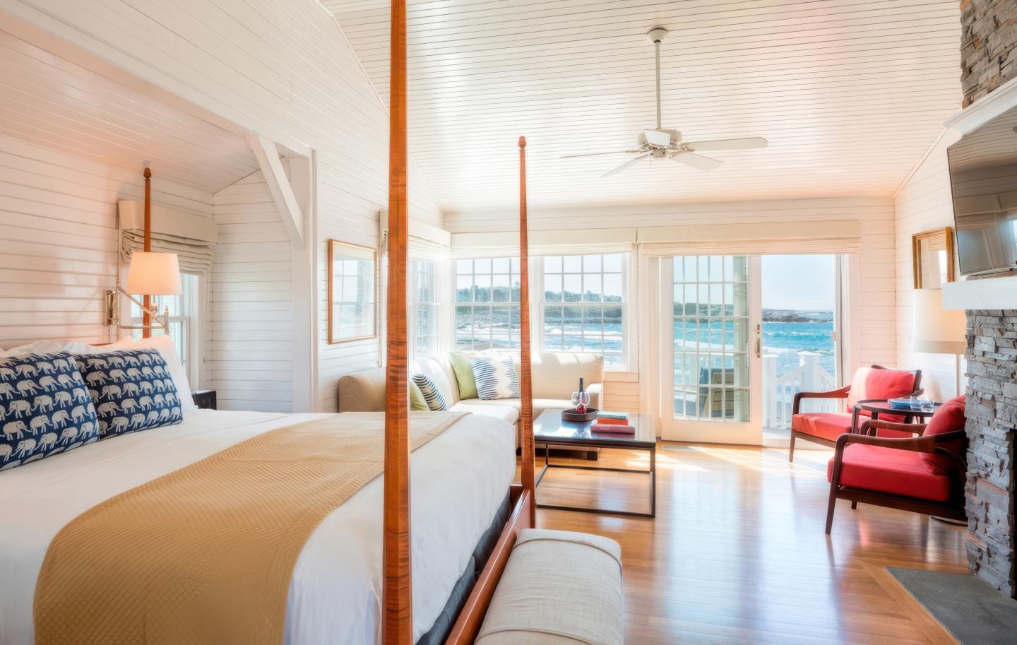 Cozy seaside bedroom with a king bed, sofa, and ocean view through large windows.