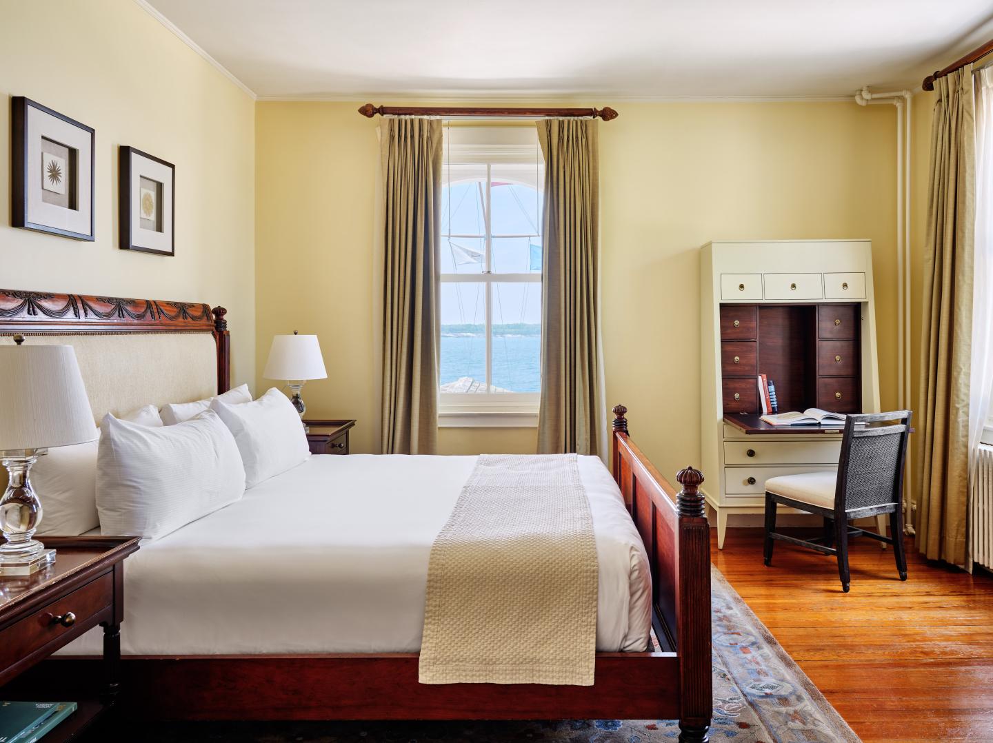 Cozy hotel room with a large bed, desk, and window view of the ocean.