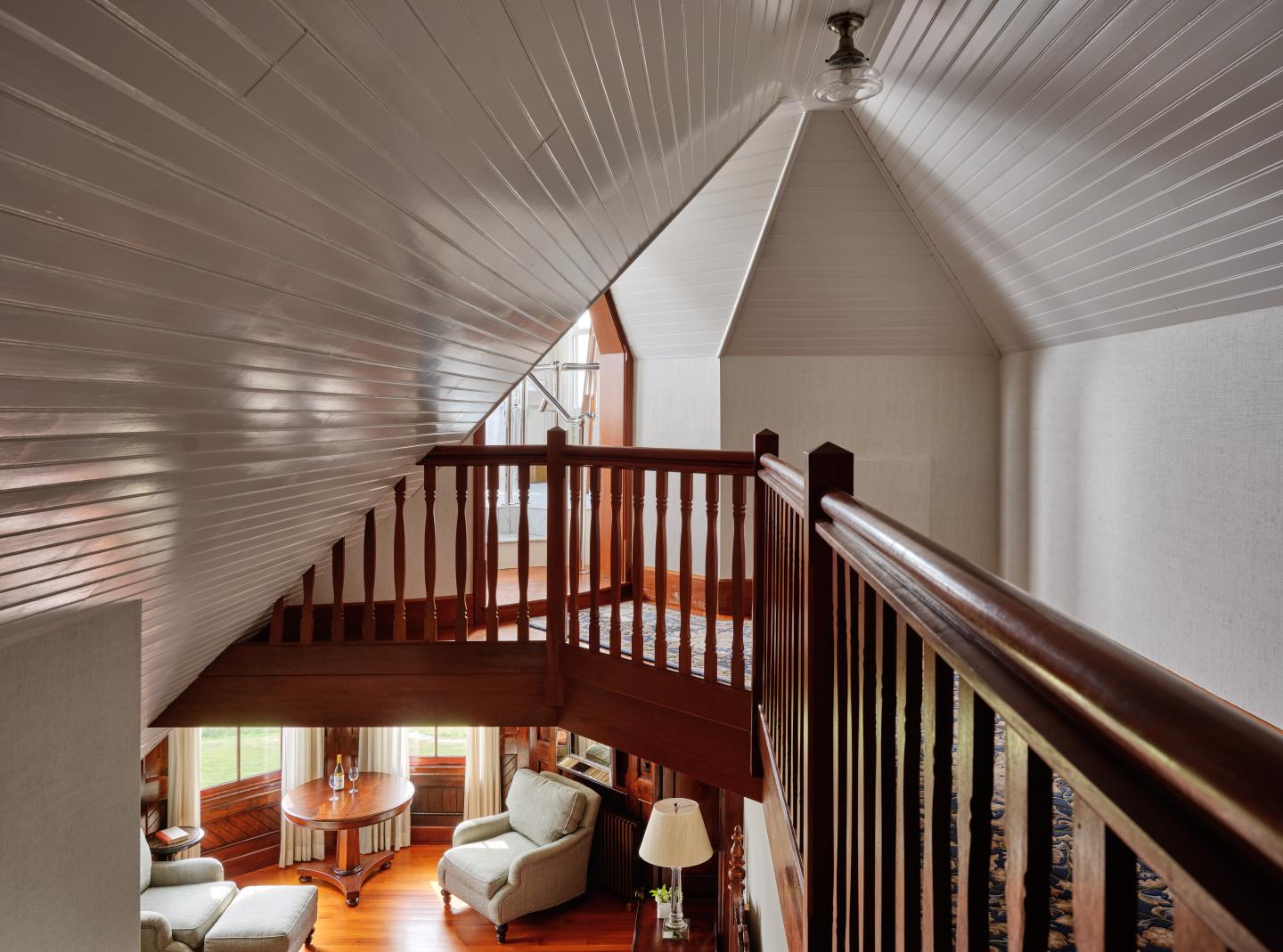 Vaulted ceiling room with wooden railing and cozy seating area below.