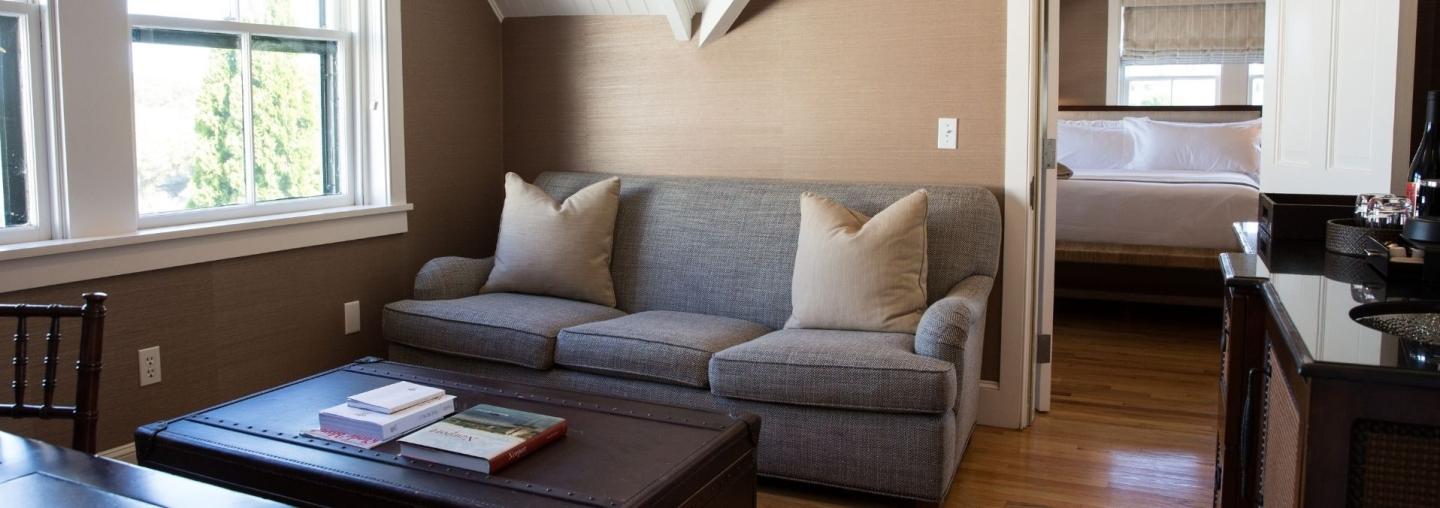 Gray sofa with beige pillows in a living room, near a coffee table and window.