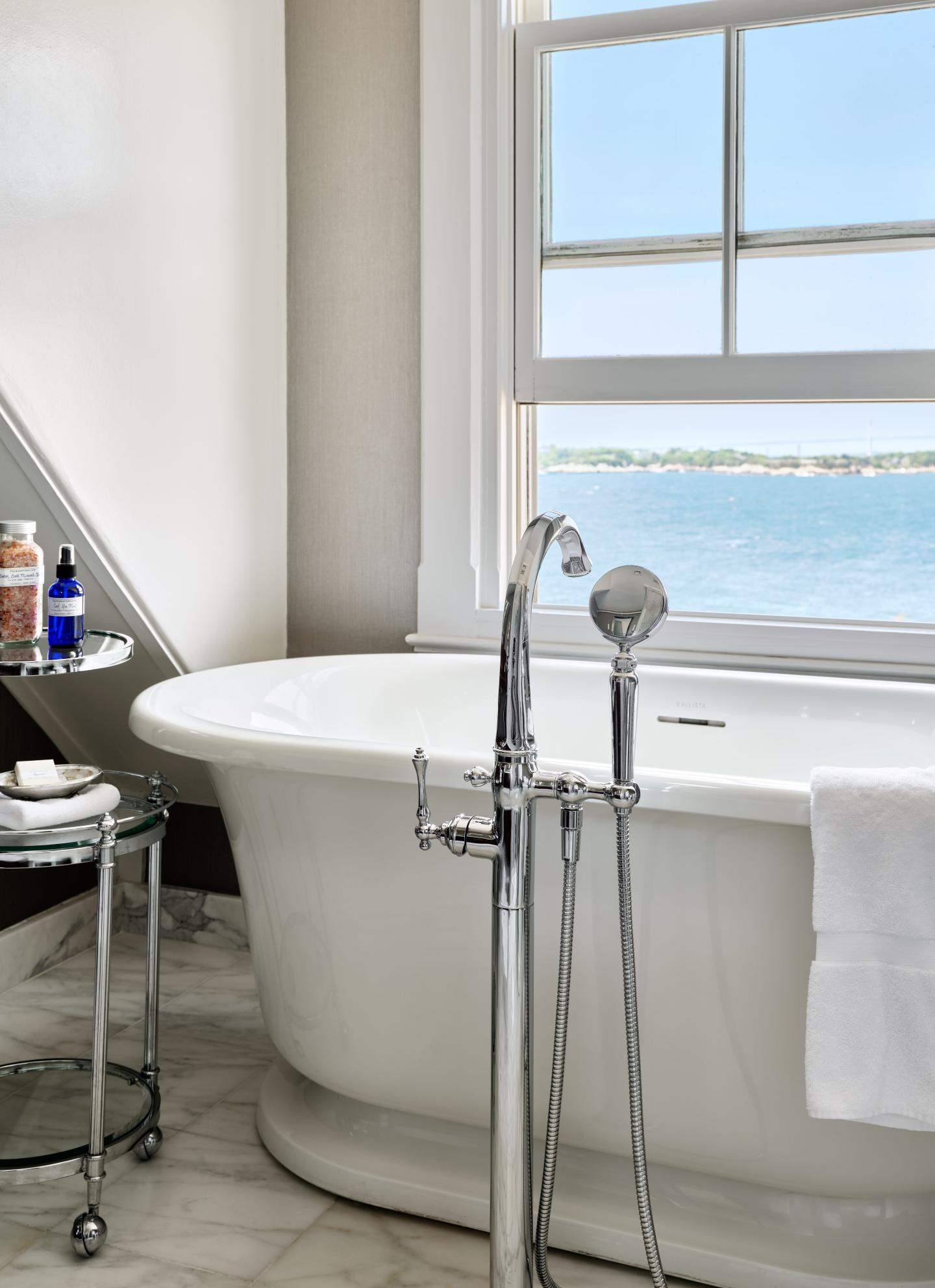 Freestanding bathtub by a window overlooking the sea.