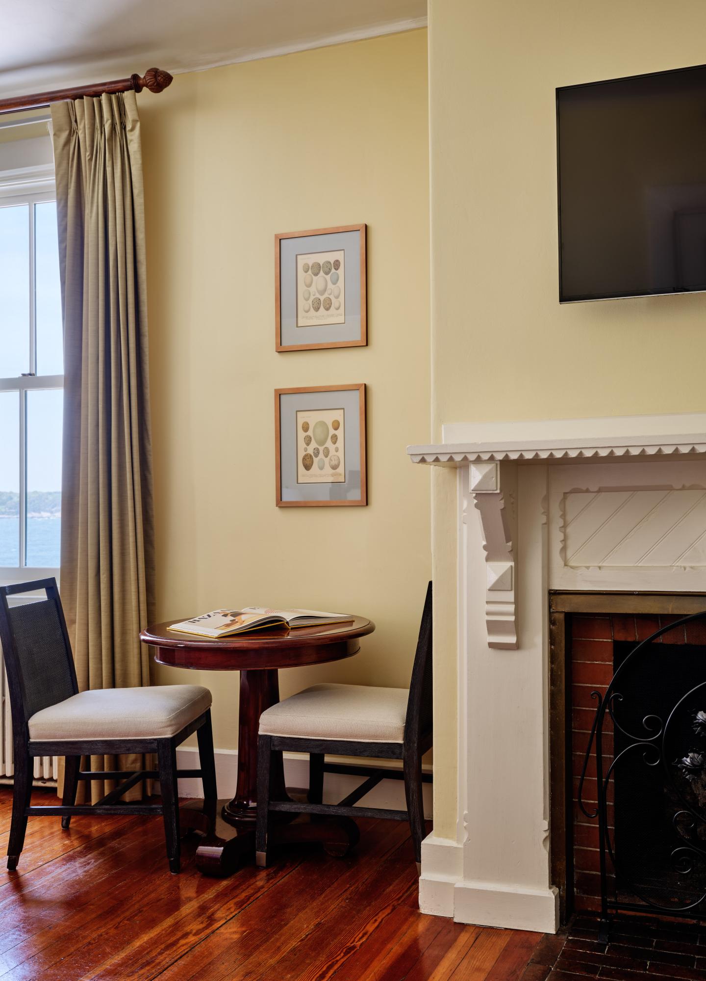 Cozy room corner with small table, two chairs, fireplace, and wall-mounted TV.