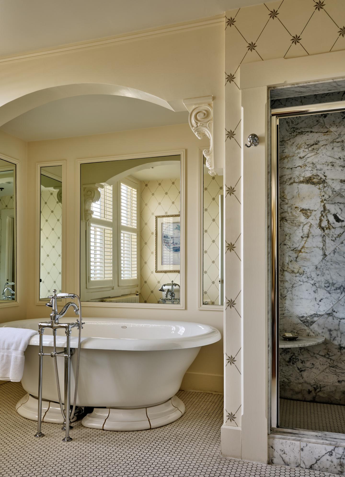 Luxurious bathroom with freestanding tub, large mirrors, and a marble shower.