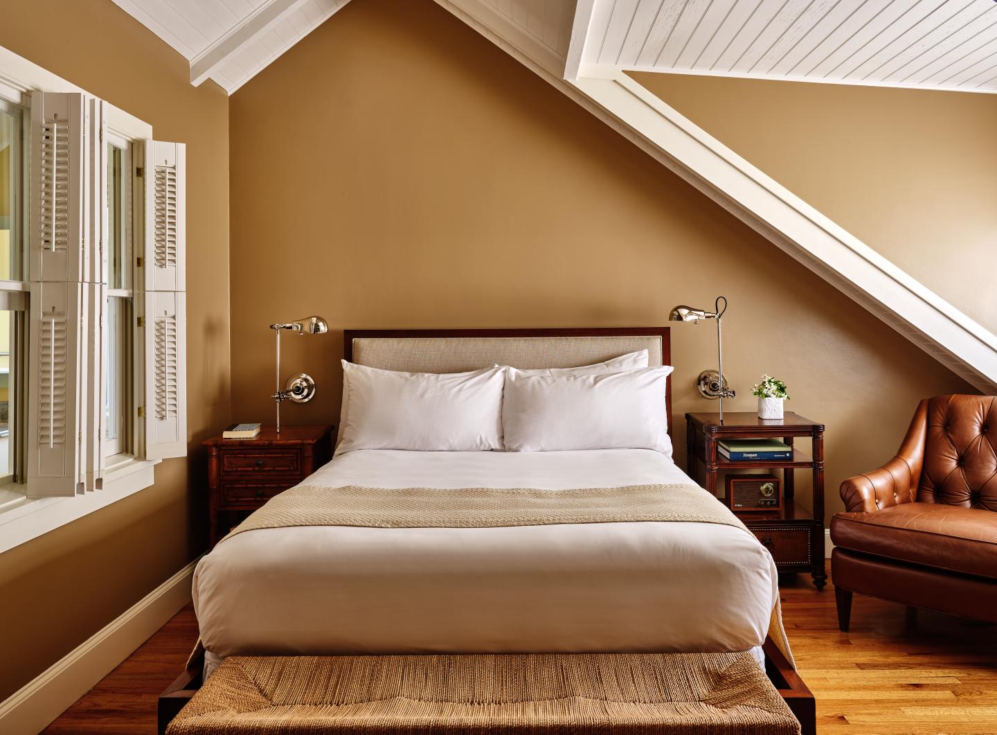 Cozy bedroom with a large bed, two side tables, and a brown armchair.