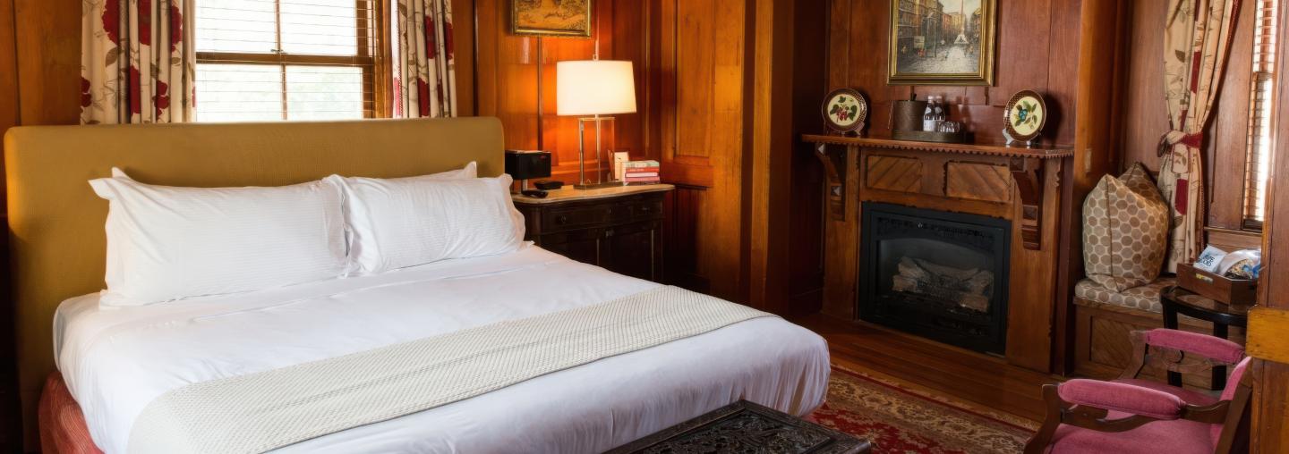 Cozy bedroom with a double bed, fireplace, and warm wooden decor.