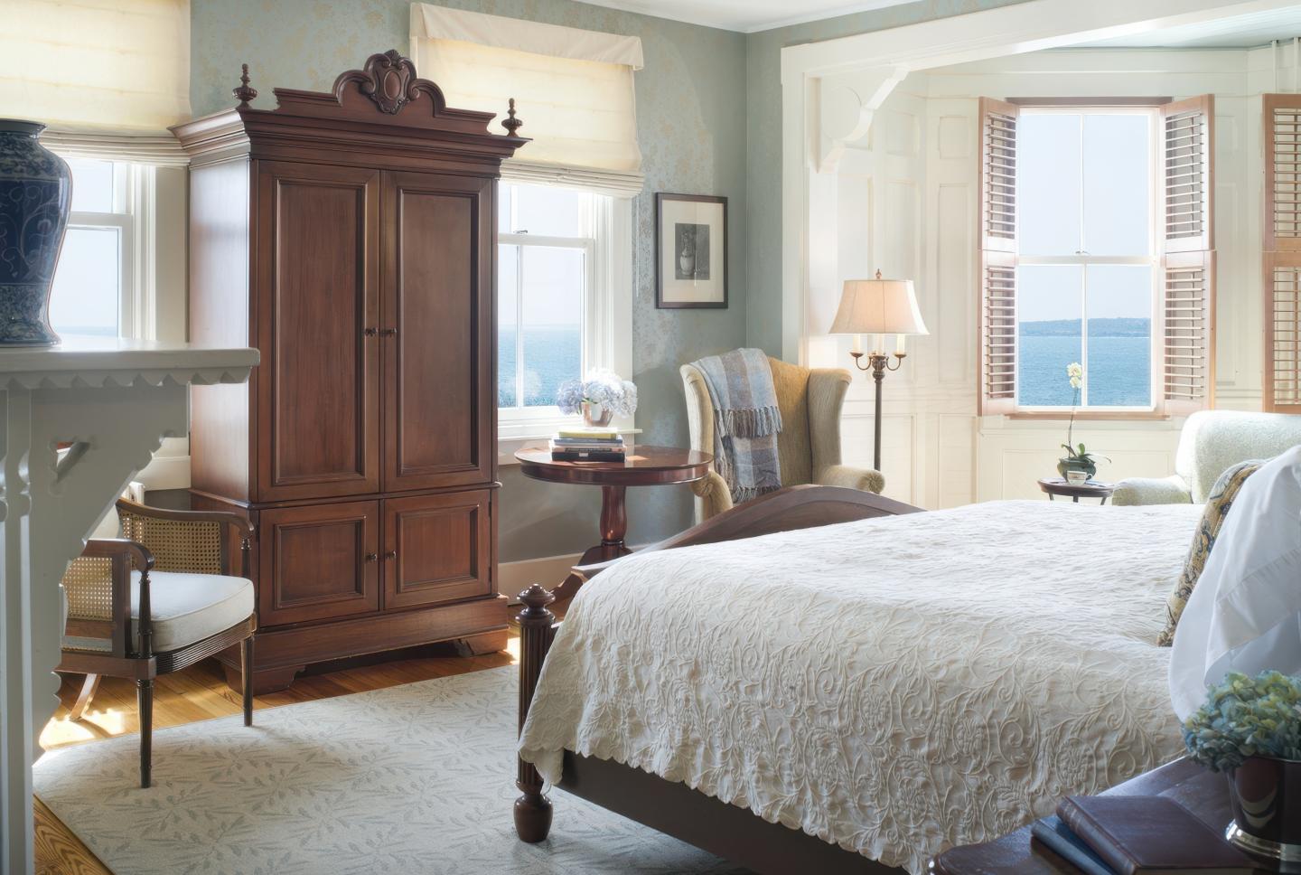 Elegant bedroom with wooden furniture, sea view, and soft lighting.