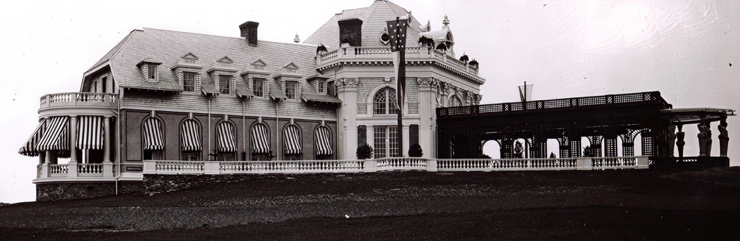 Grand vintage building with tall windows and a covered porch.