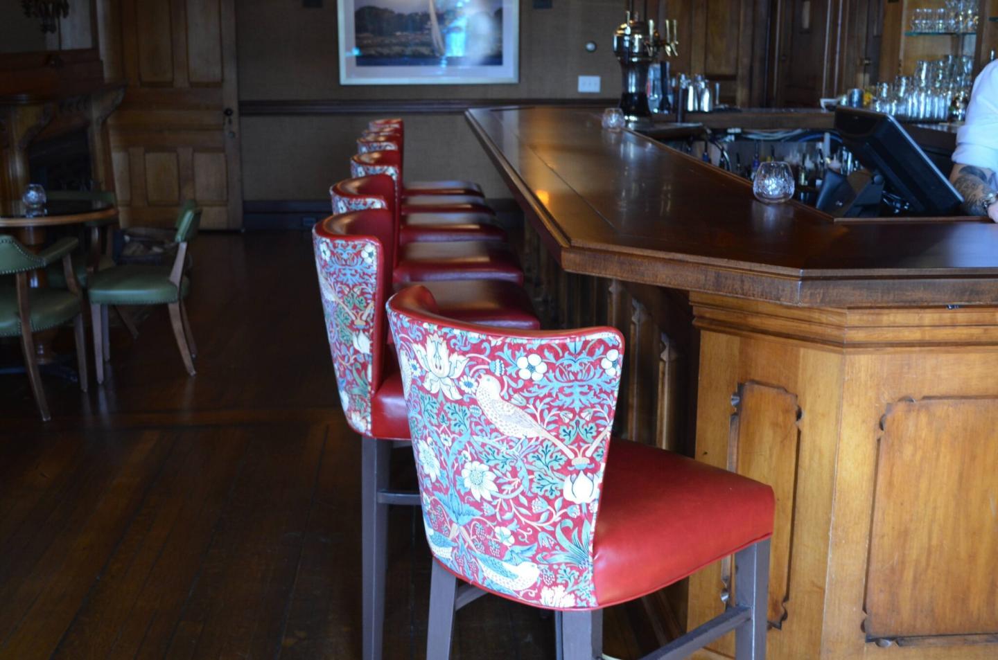 Bar with floral red cushioned stools and wooden countertop.
