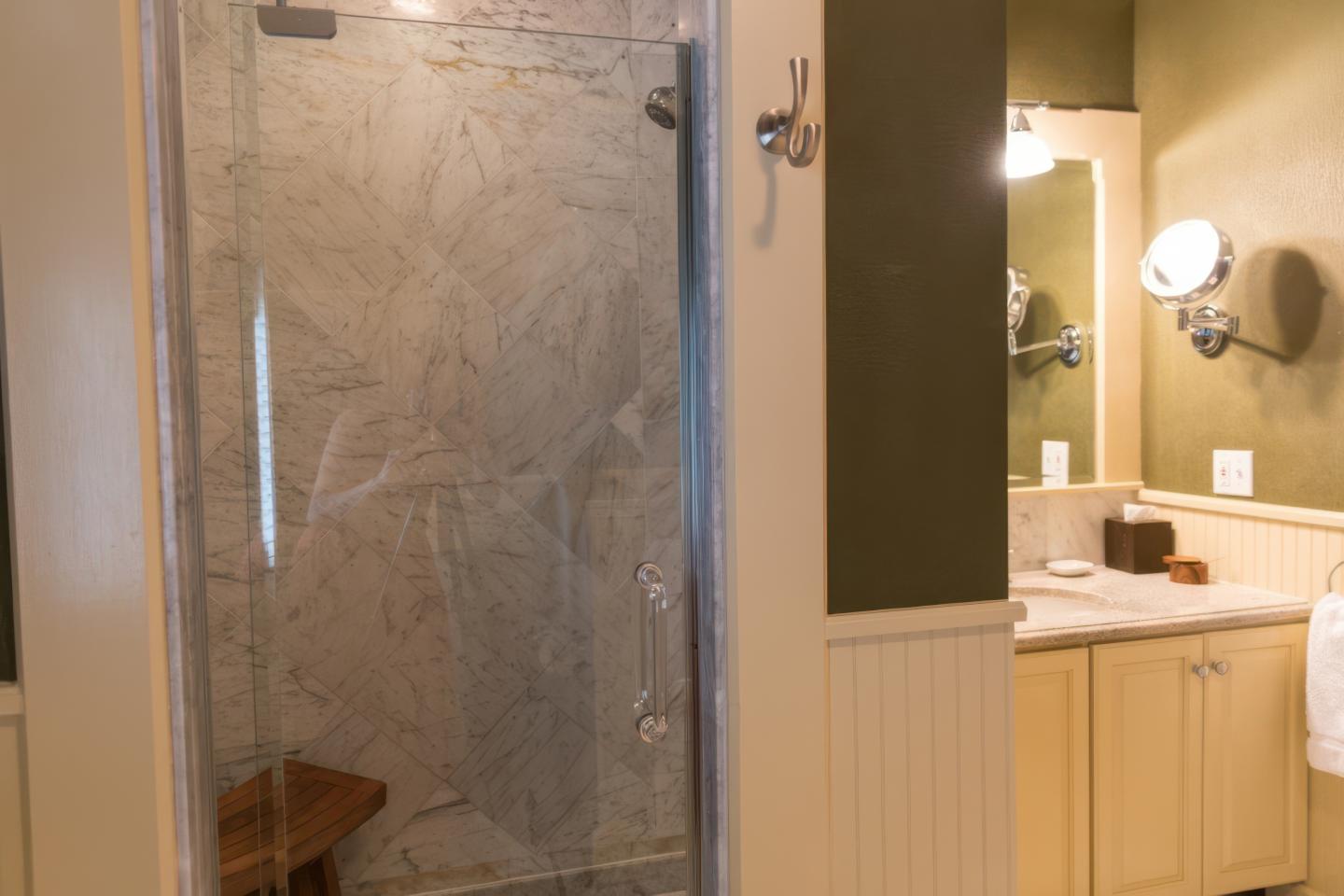 Bathroom with marble shower and wooden bench.