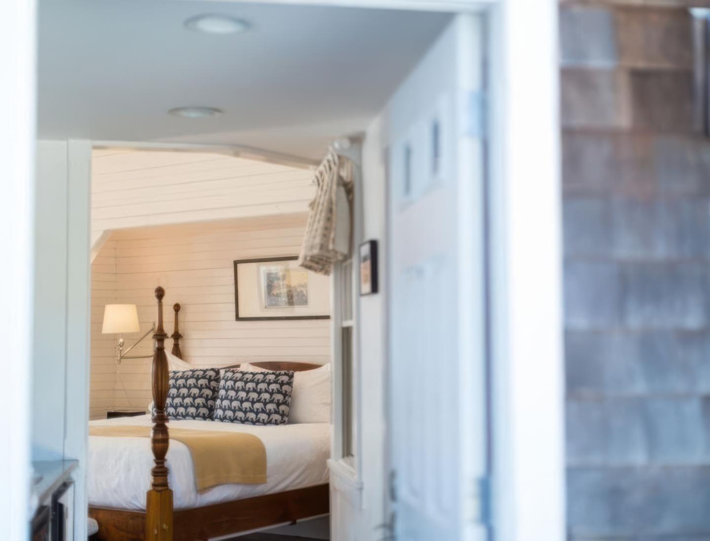 Cozy bedroom with a four-poster bed, lamp, and framed picture on the wall.