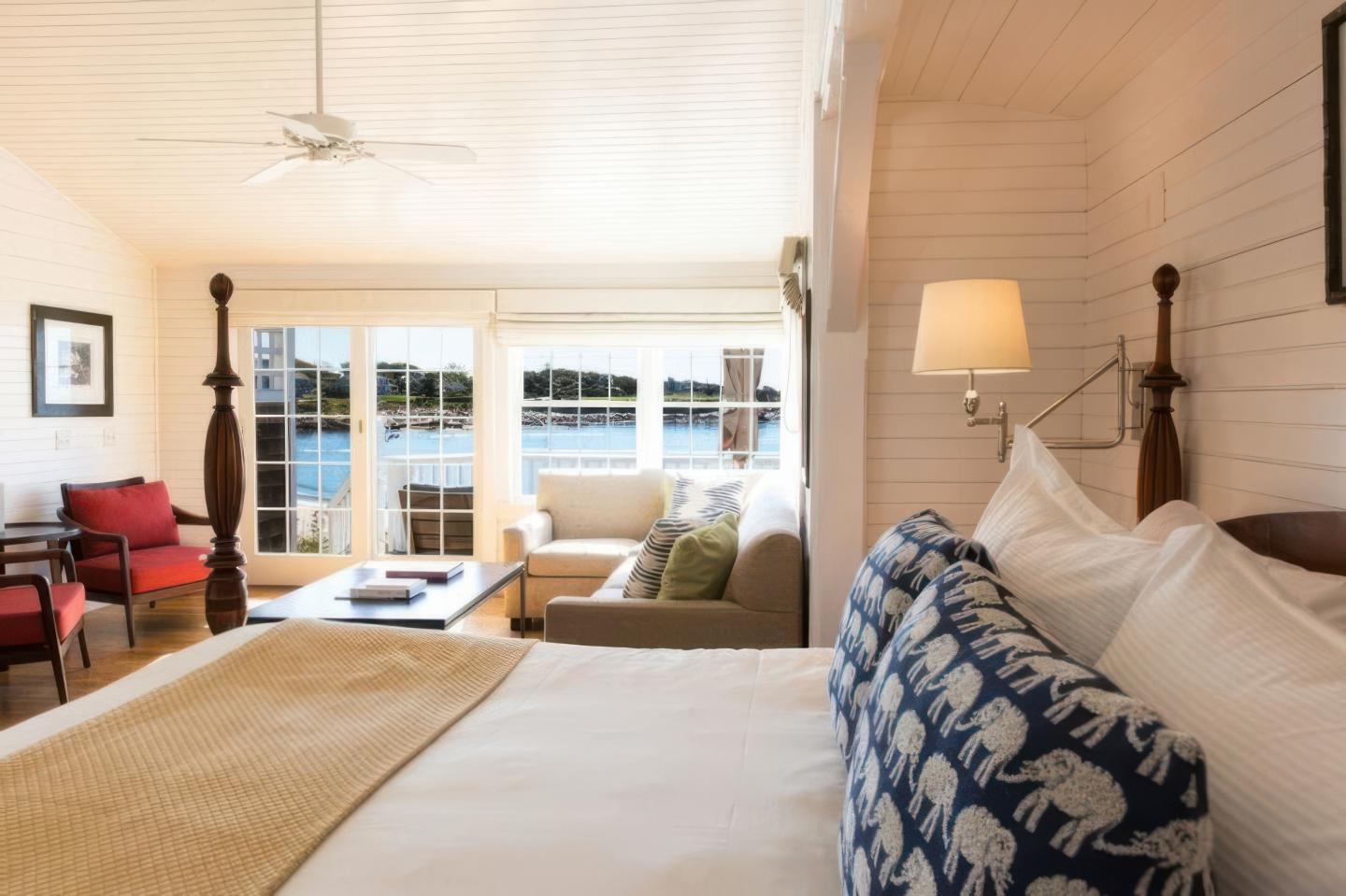 Cozy bedroom with a patterned pillow, overlooking a sunlit living room with a view.