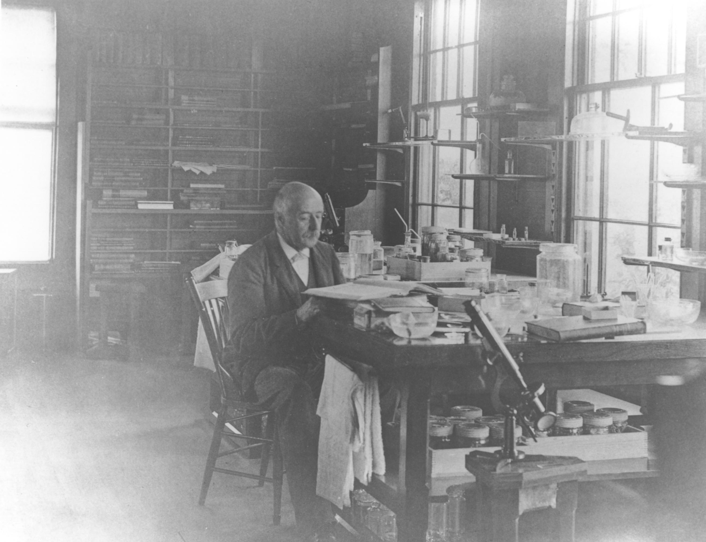 Man sitting at a cluttered desk in a dimly lit workshop.