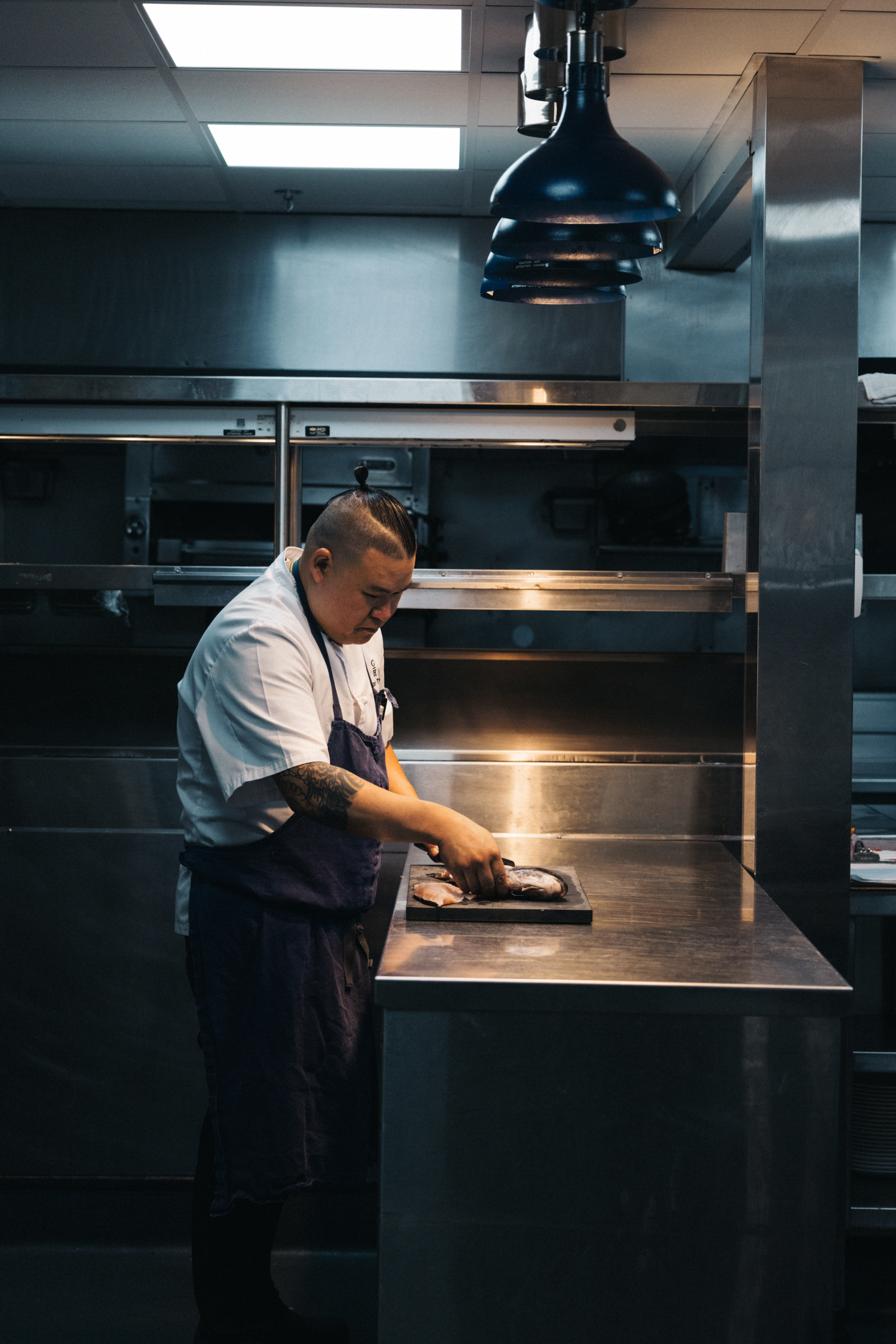 Chef preparing food in a dimly lit kitchen.