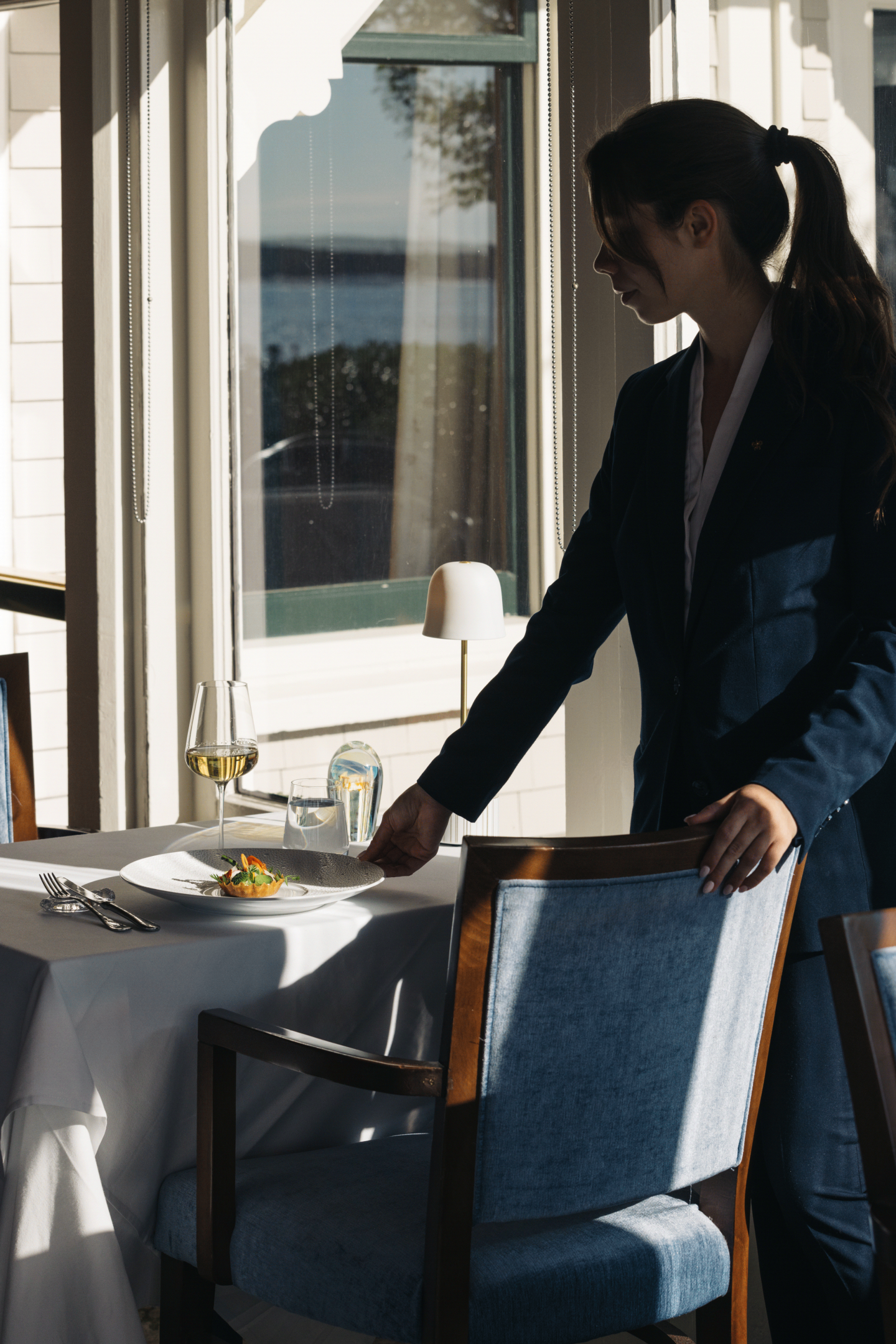 Server setting a table in a sunlit restaurant.
