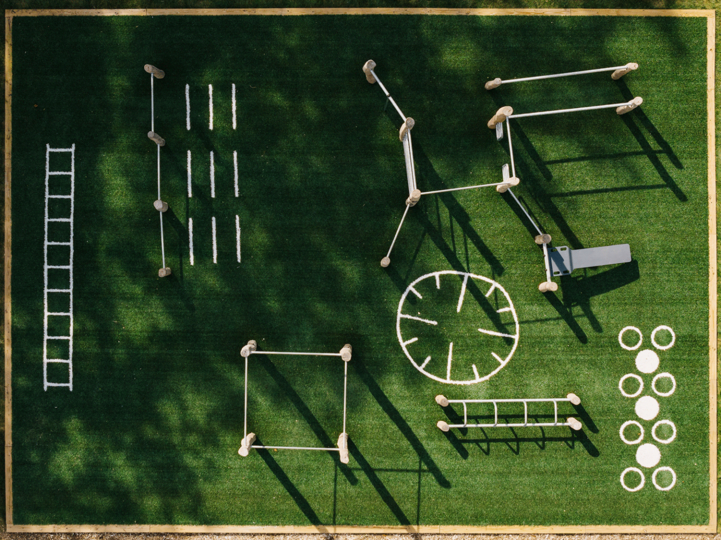 Outdoor fitness course on green grass, viewed from above.