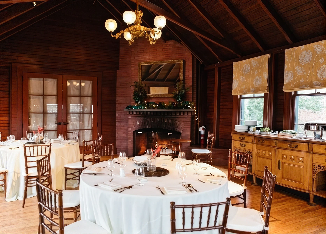 Cozy dining room with round tables, wooden chairs, brick fireplace.