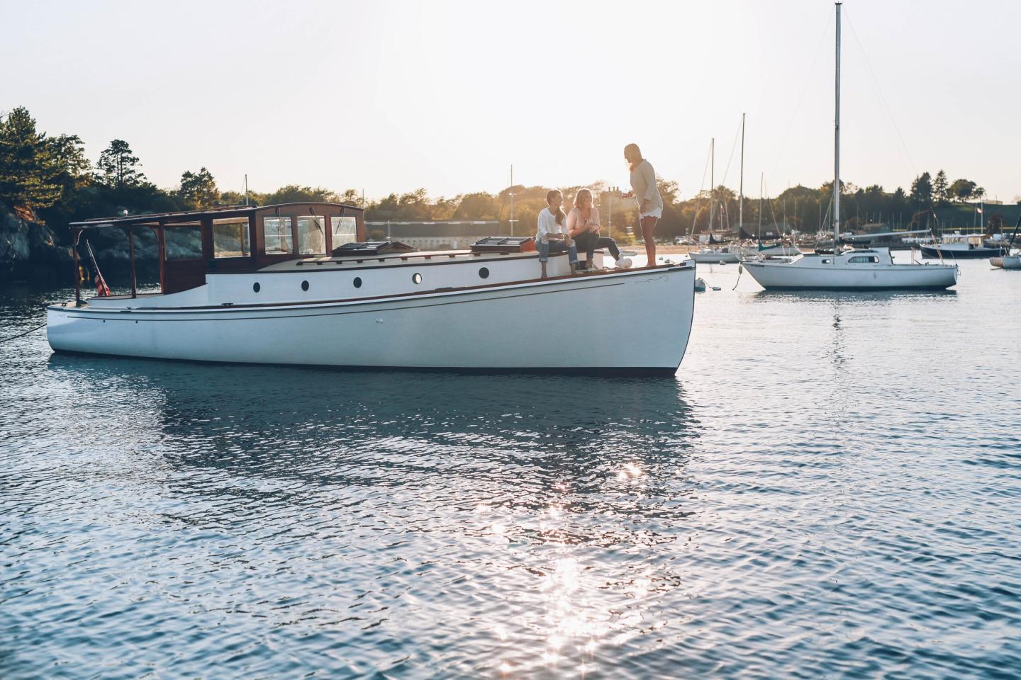 People standing on a boat in a sunny harbor.