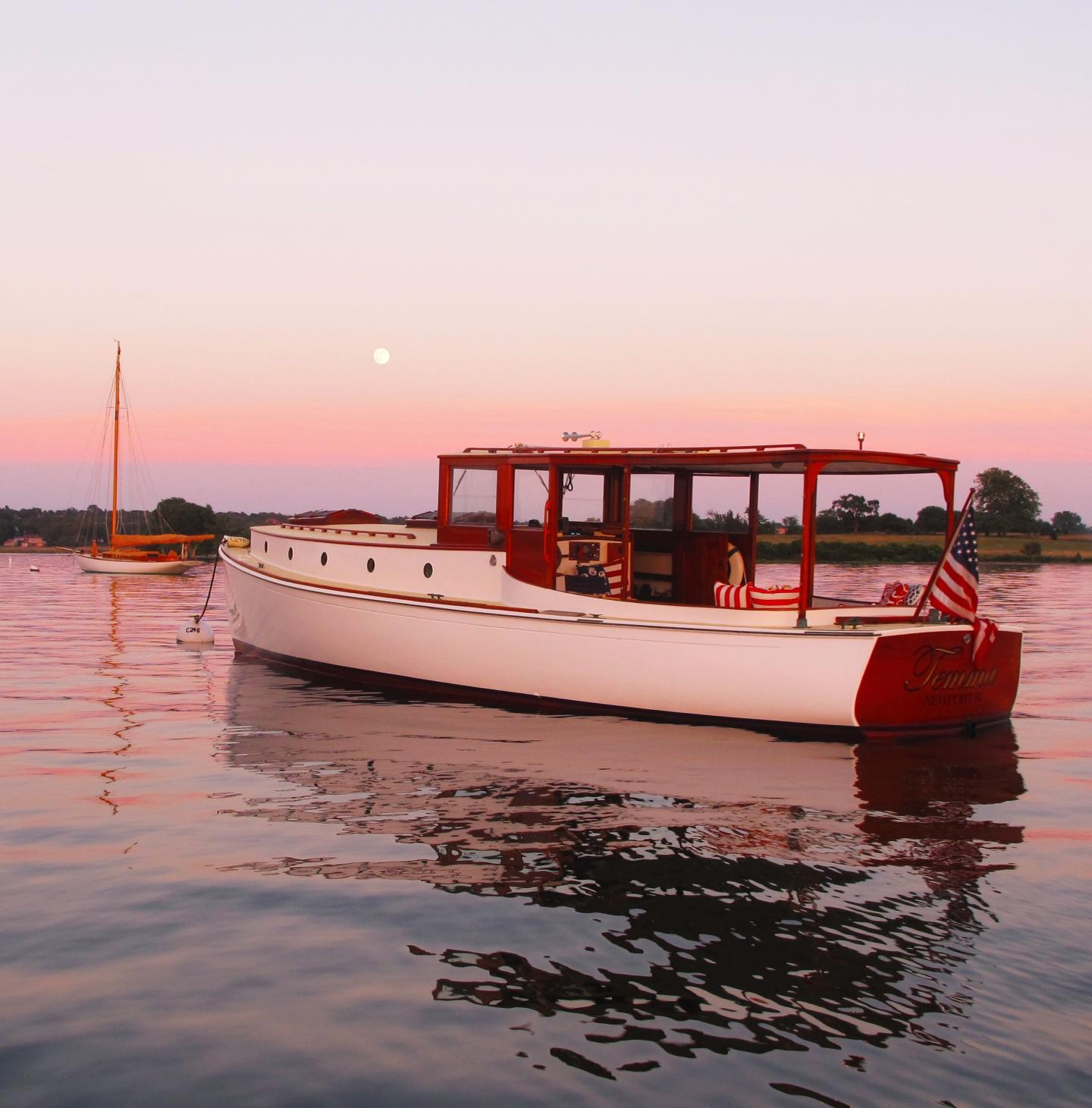 White boat on calm water during sunset with pink sky.