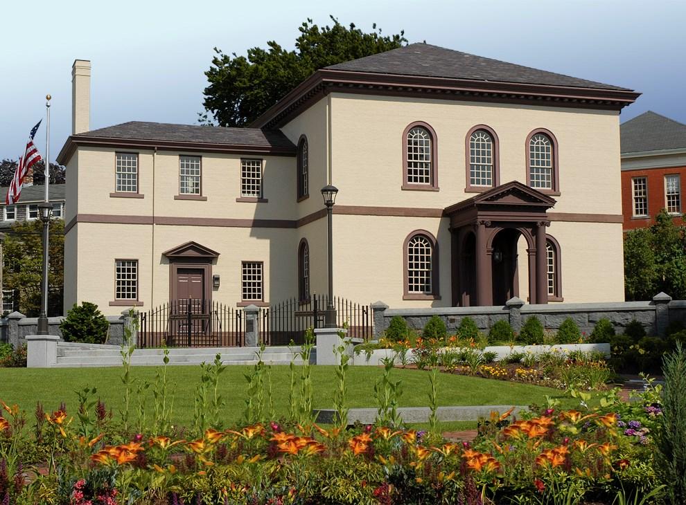 Historic-style building with arched windows and garden in front.