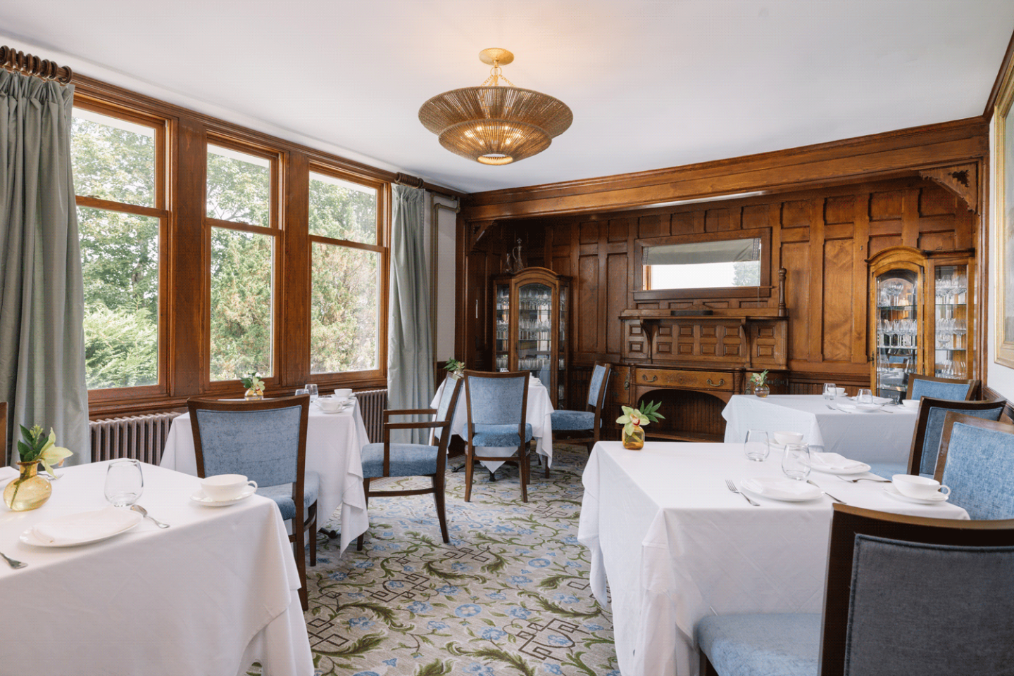 Elegant dining room with wood paneling and white tablecloths.