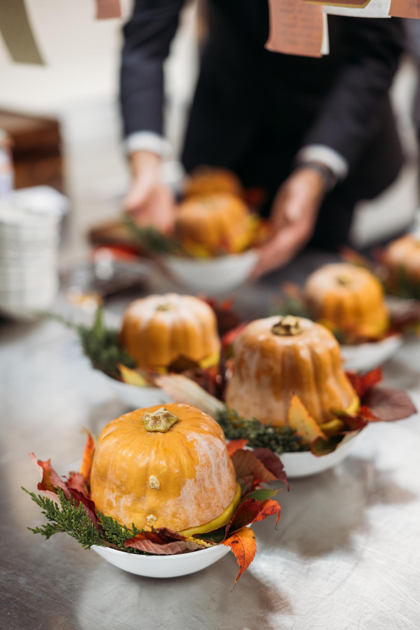 Small pumpkin-shaped cakes on plates, garnished with leaves.