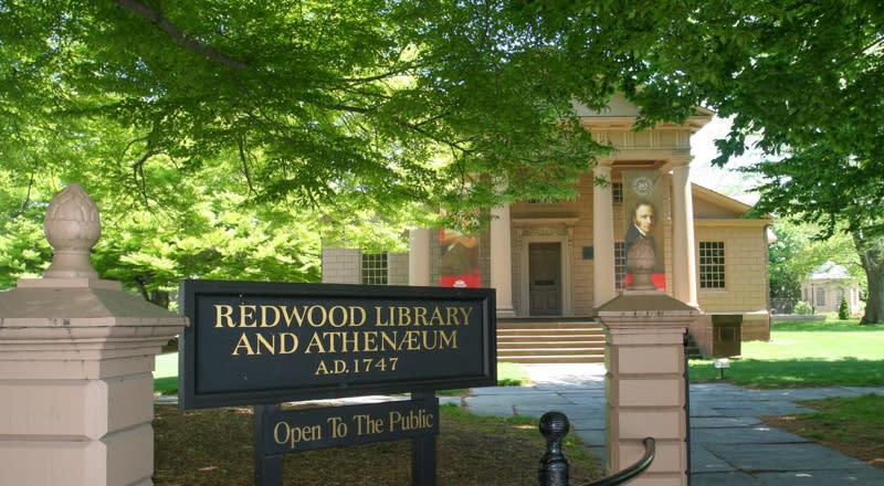 Redwood Library with sign and trees in sunlight.