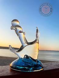 Glass anchor ornament on ledge with ocean view at sunset.