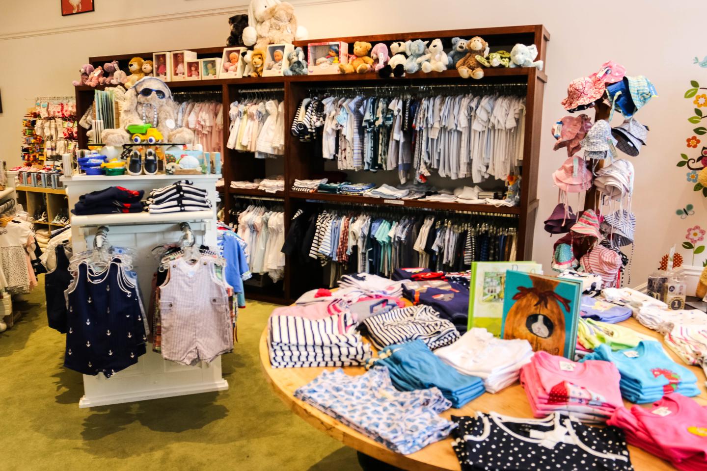Children's clothing store with shelves and tables of colorful clothes and accessories.