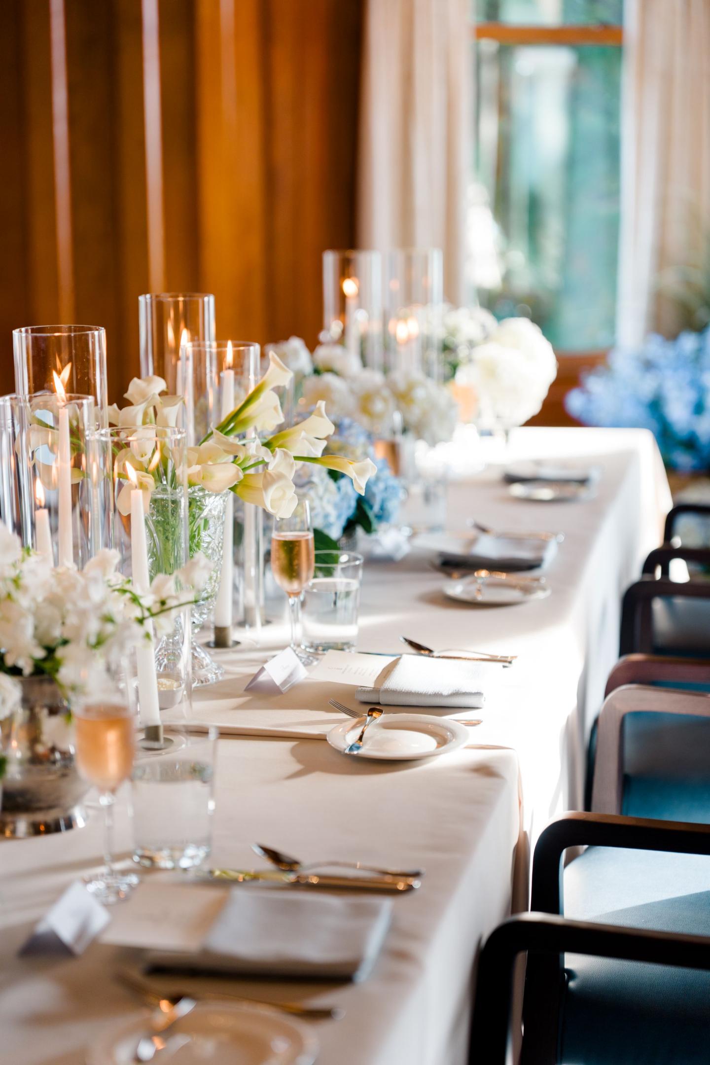 Elegant dining table with flowers and candles in soft lighting.