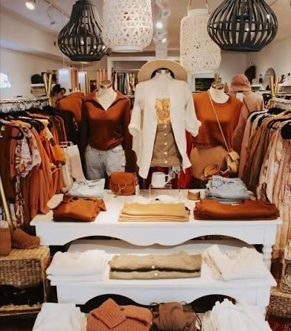 Clothing boutique with warm-toned outfits displayed under stylish lighting.