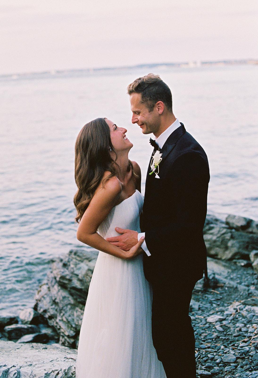 Bride and groom smiling by the ocean.