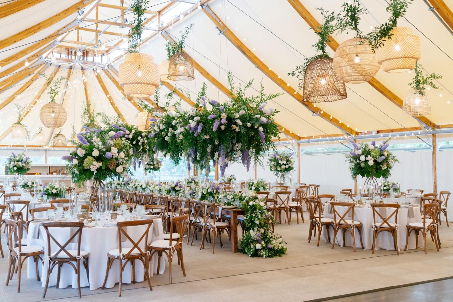 Elegant wedding tent with floral decor and round tables.