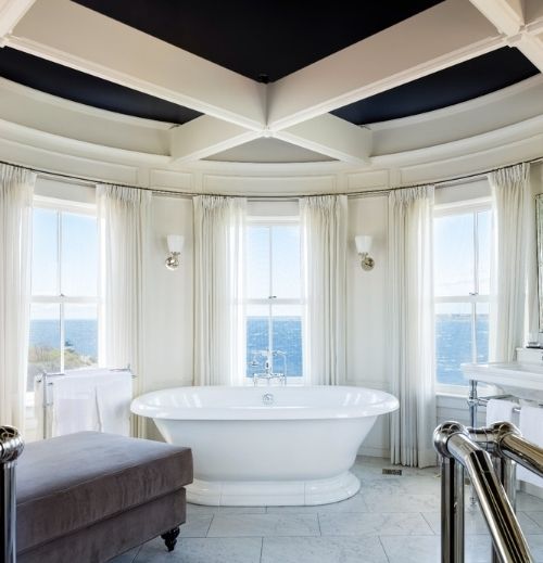 White bathtub overlooking the ocean inside bathroom near sofa at Castle Hill Inn in Newport, RI