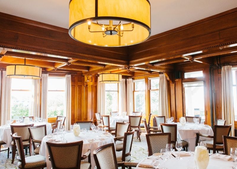 Dining room with tables and chairs with white linens and glassware at Castle Hill Inn in Newport, RI