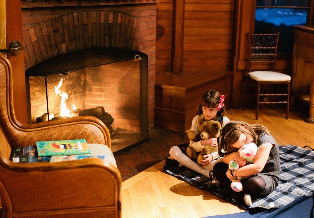 Children holding stuffed animals in front of chair next to fireplace at Castle Hill Inn in Newport, RI