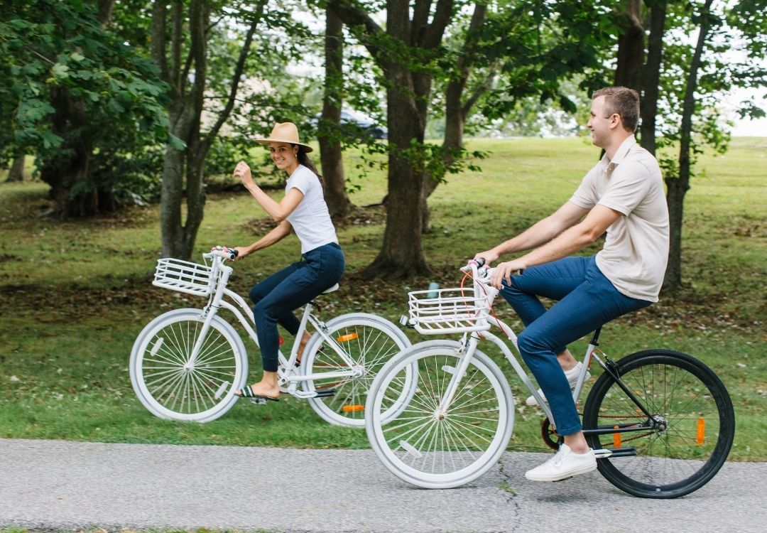 Two people on bicycles riding on stone pathway near trees at Castle Hill Inn in Newport, RI