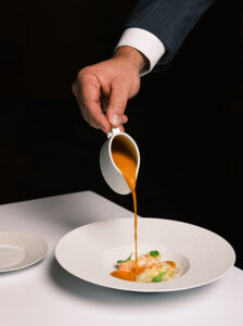 Server pours soup over lobster at table