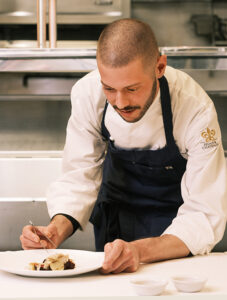 Chef preparing dinner plate with tweezers