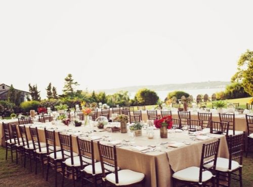 Banquet setup with black and white tables and chairs, tan linens on grass with floral centerpieces at Castle Hill Inn in Newport, RI